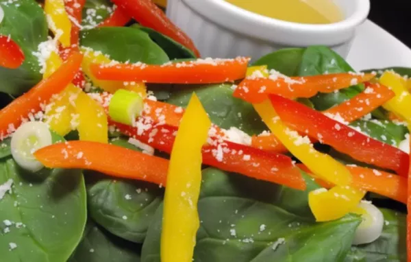 A refreshing and nutritious salad with a mix of vibrant spinach and red peppers.