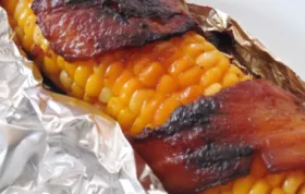 Delicious and smoky grilled corn on the cob wrapped in crispy bacon strips